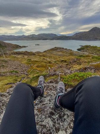 A hiker enjoying the scenery of Skipfjorden from Torvhamn trail on Mageroya Island, Norway