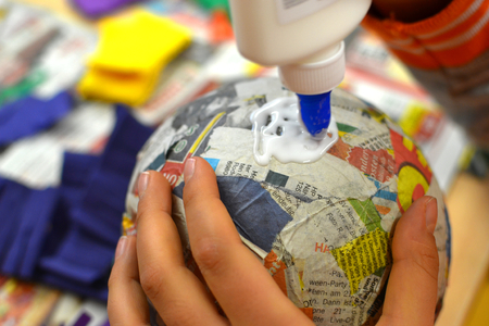 Children hands are making a pinata with colorful paper and glue.の写真素材