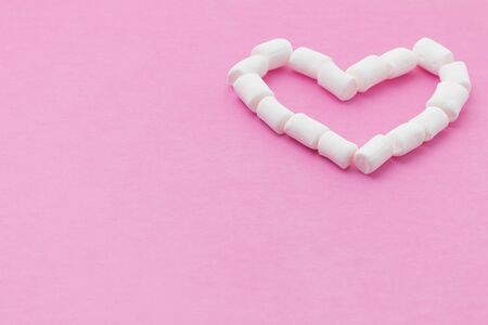 a shape of heart made of small marshmallows on a pink background, low viewの写真素材