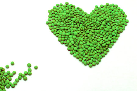a shape of heart made of lentils coloured in bright green, isolated on a white backgroundの写真素材