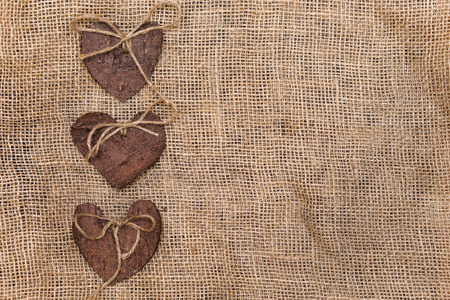 Three (3) decorative hearts made from tree bark on sackcloth, positioned on left side of the photo. Hearts decorated with eco twine.の写真素材