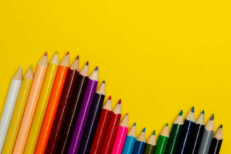 Overhead view of colorful pencils on yellow backdrop. Poster design idea is.の写真素材