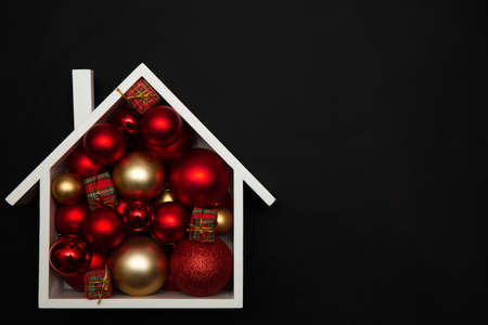 Christmas background of a festive house with Christmas tree baubles. Christmas card design with festive decoration on black background. Christmas and New Year decorations with copy space.の写真素材