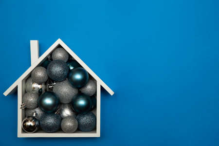 Christmas background of festive house with Christmas tree baubles. Christmas card design with festive decoration on blue background. Christmas and New Year decorations with copy space.の写真素材