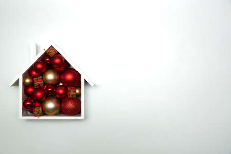Christmas background of a festive house with Christmas tree baubles. Christmas card design with festive decoration on white background. Christmas and New Year decorations with copy space.の写真素材