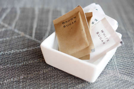 Brown sugar and White sugar in pack on table.の写真素材