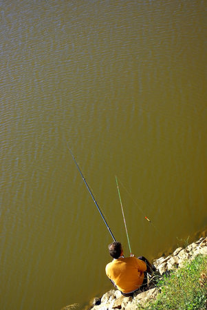 Fisherman Sitting on a River Bank