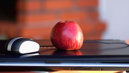 Laptop and mouse with red apple.の写真素材