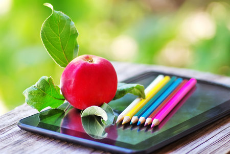 Digital tablet with colored pencils and apple