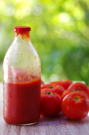 bottle of homemade ketchup and tomatoes on tableの写真素材