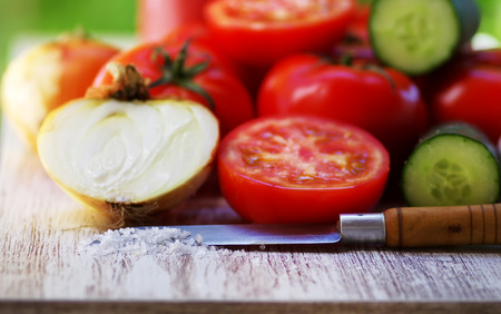 Red tomatoes , onion, salt, kitchen knife on tableの写真素材