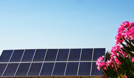 Solar panels on blue sky with bouquet of pink flowersの写真素材