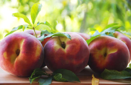 Ripe peaches and leaves on tableの写真素材