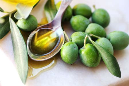 spoon of olive oil and olives fruit on tableの写真素材