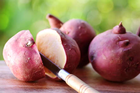 sweet potatoes and knife on wooden table, green backgroundの写真素材
