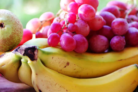 bunch of red grapes and bananas on wooden tableの写真素材