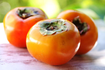 ripe persimmon fruits on wooden tableの写真素材