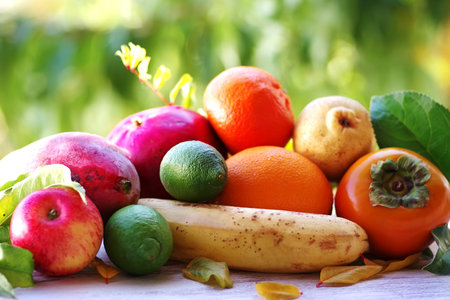 persimmon, pomegranate, apple, other fruits and leaves on the tableの写真素材