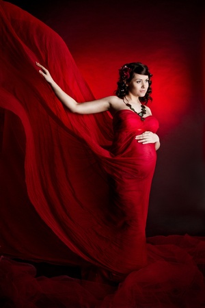  Pregnant woman in red waving flying dress. Lookingforward.の写真素材