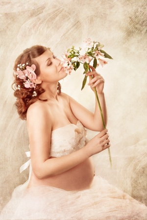  Pregnant woman sniffing flowers and dreaming. Sitting with closed eyesの写真素材