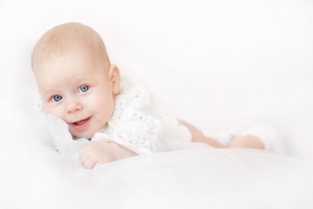 Smiling adorable baby lying over white backgroundの写真素材