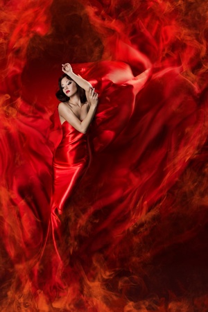 Beautiful woman in red waving silk dress as a fire flame. Looking down.の写真素材