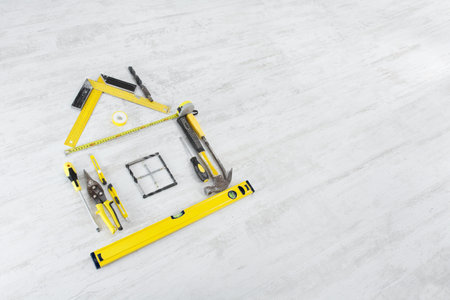 Tools in the shape of house over wooden background. Home improvement concept.