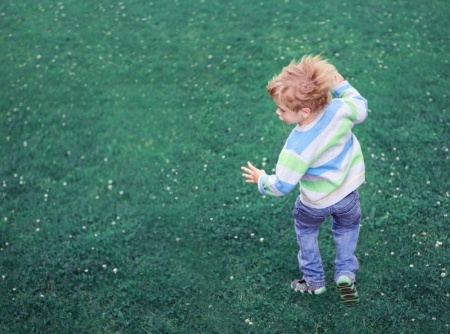 Child jumping carefree outdoors over green grass background. Happiness and freedom concept.の写真素材