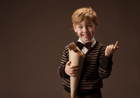 Child holding sweets in paper package  Boy in retro style  Brown background の写真素材