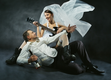 Wedding couple celebrating, singing, drinking and playing guitar. Bride in rock style. の写真素材
