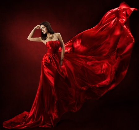 Woman in red waving dress dancing with flying fabricの写真素材