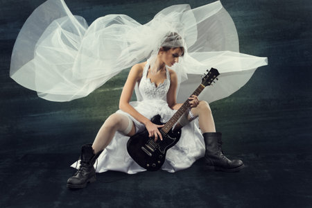 Bride playing rock guitar over artistic dark backgroundの写真素材