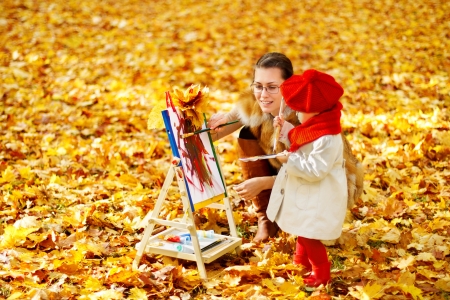 Mother and child drawing on easel in autumn park. Creative kids development concept.の写真素材