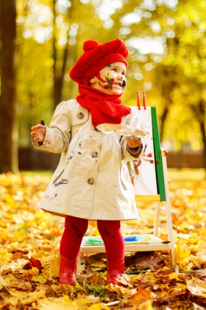 Child drawing on easel in Autumn Park. Creative kids development concept.の写真素材