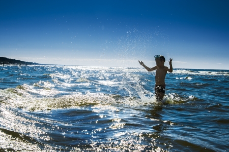 Child silhouette and water splash in the sea. Summer time vacationの写真素材