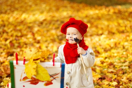 Child drawing on easel in Autumn Park. Creative kids development concept.の写真素材