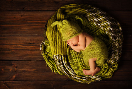 baby newborn sleeping in woolen hat on brown wooden background
の写真素材
