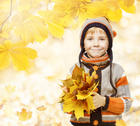 autumn kid in leaves, little child in woolen hat, knitted clothing for October seasonの写真素材