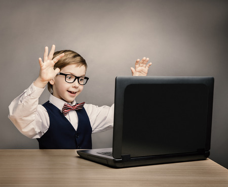 Child With Laptop, Little Boy in Glasses Happy Amazed Looking at Computer, School Kid Raised Hands over Gray Background, Internet Conceptの写真素材
