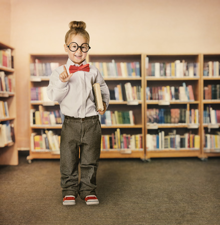 School Kid in Library, Child in Glasses with Book, Little Girl Student Finger Point Up, Bookcase Shelvesの写真素材