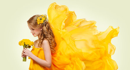 Young Girl Portrait with Yellow Flowers Dandelion Bouquet, Fashion Model Posing with Flying Fabricの写真素材