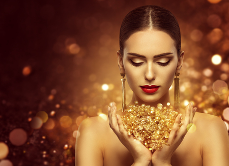 Fashion Model Holding Gold Jewelry in Hands, Woman Golden Beauty, Beautiful Girl Makeup and Luxury Jewelleryの写真素材