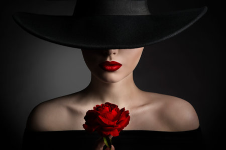 Red Rose Flower Woman Lips and Black Hat, Elegant Fashion Model Beauty Portrait, Lady in Wide Broad Brim Hat on Dark Backgroundの写真素材