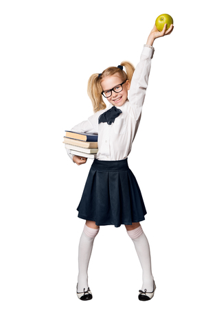 School Girl, Happy Pupil in Uniform with Books Raising Up Apple, Funny Kid Full Length Portrait Isolated over White Backgroundの写真素材