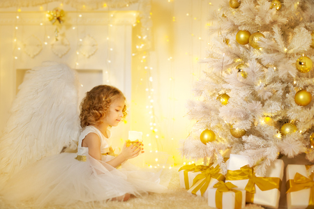 Angel Child and Christmas Tree with Presents Gifts, Kid Girl Costume holding Candle Lightの写真素材