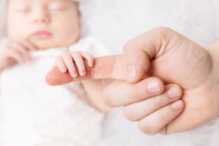Newborn Baby Holding Mother Hand, Mom Finger and New Born Kid on White, Help Conceptの写真素材
