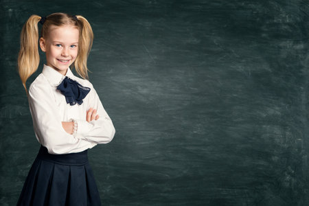 School Girl Child on Blackboard Background, Happy Pupil Kid in Retro Dress over Black Chalk Board