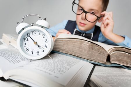 Child Reading Books behind Clock Alarm, School Boy Learning Hard Lessons, Time and Educationの写真素材