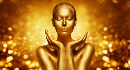 Gold Skin, Beautiful Woman holding Golden Beauty in Hands, Fashion Body Art Make Upの写真素材