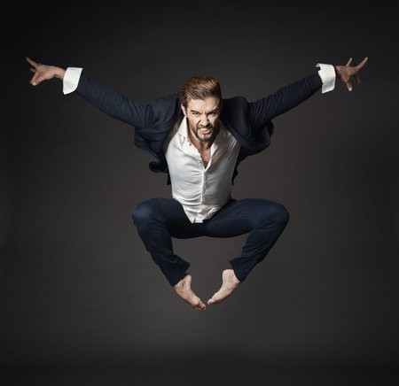 Handsome Man in Business Suit Jumping in Air, Full Length Young Ballet Dancer over Black Background